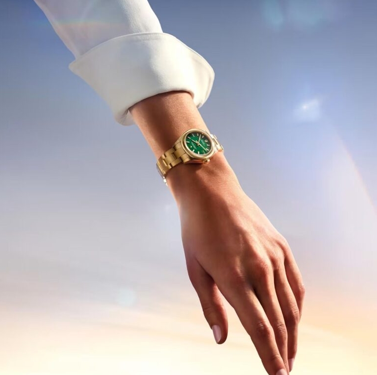 Oyster Perpetual 28 with a green dial and yellow gold bracelet shown on the wrist.